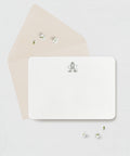 White card with a monogram ith a beige envelope against a light gray background