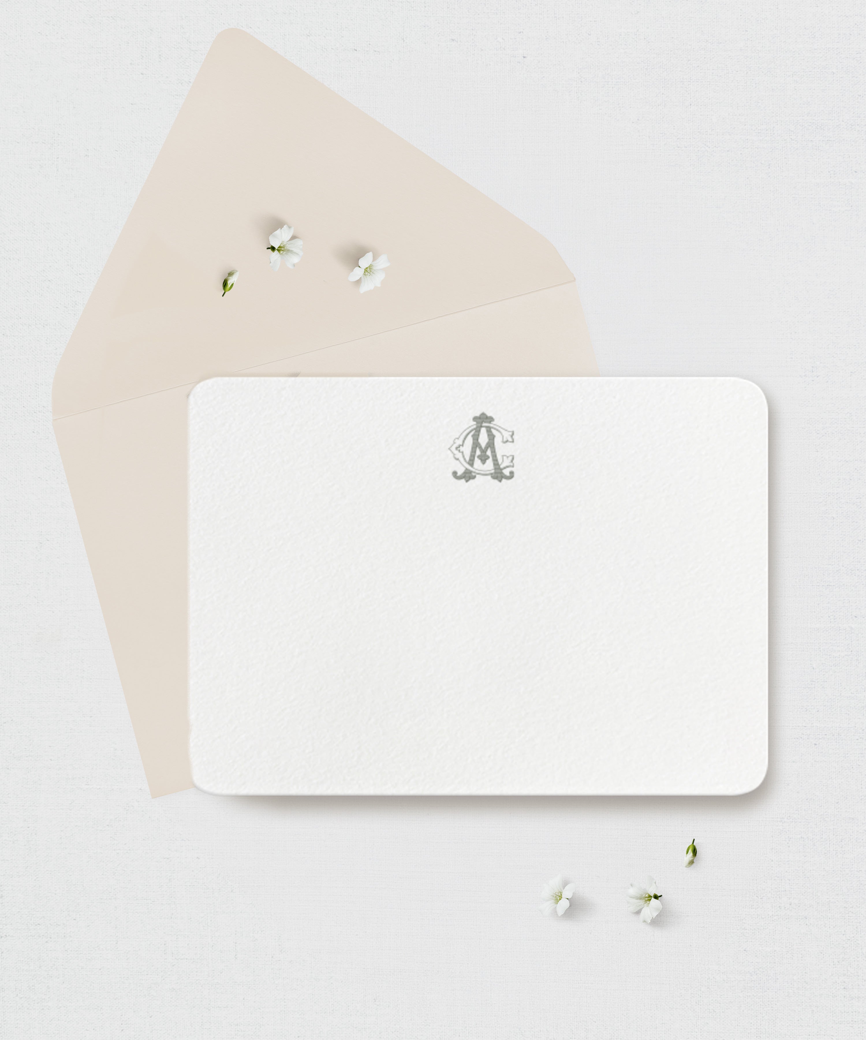 White card with a monogram ith a beige envelope against a light gray background