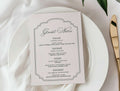 White plate with a menu card, gold knife, and white flowers on a white tablecloth.