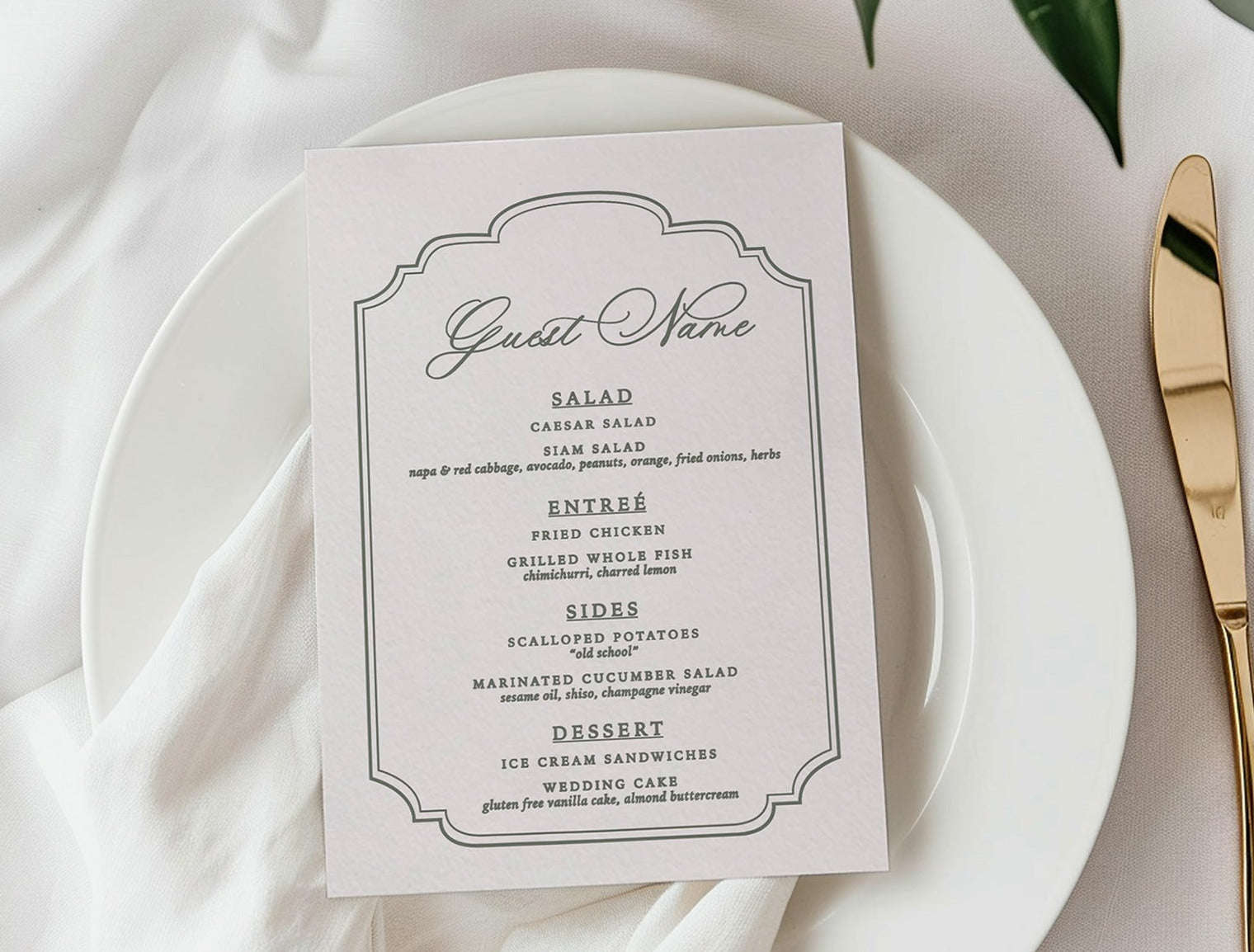 White plate with a menu card, gold knife, and white flowers on a white tablecloth.