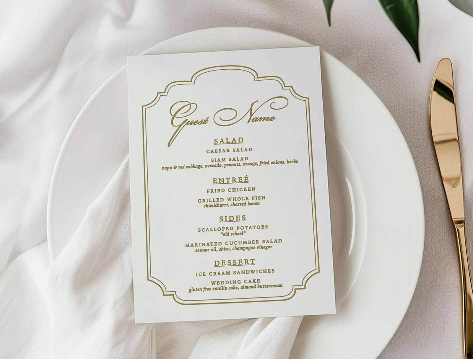 White plate with a gold-rimmed menu card on a white tablecloth with flowers and cutlery.