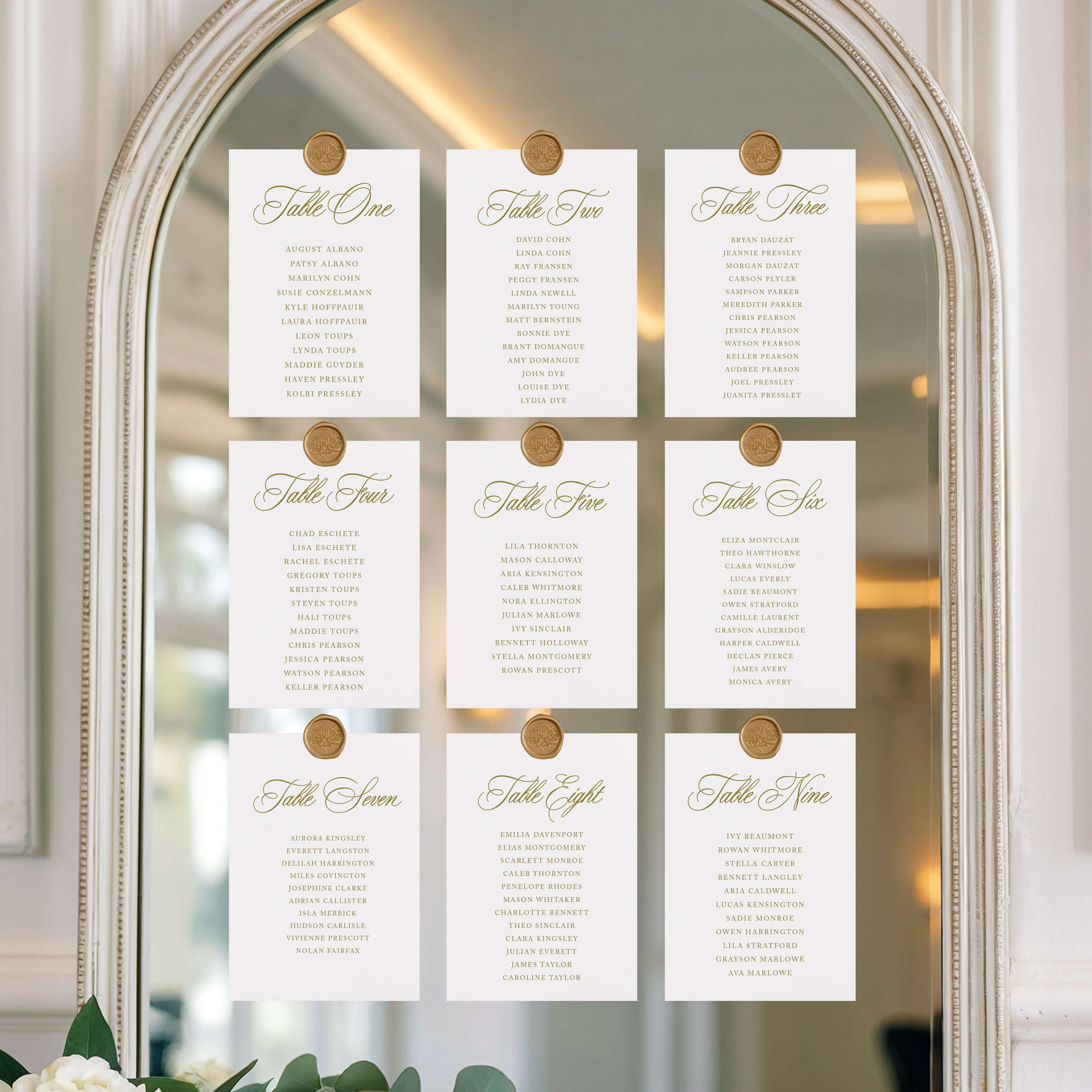 Table seating chart on a decorative mirror with gold clips