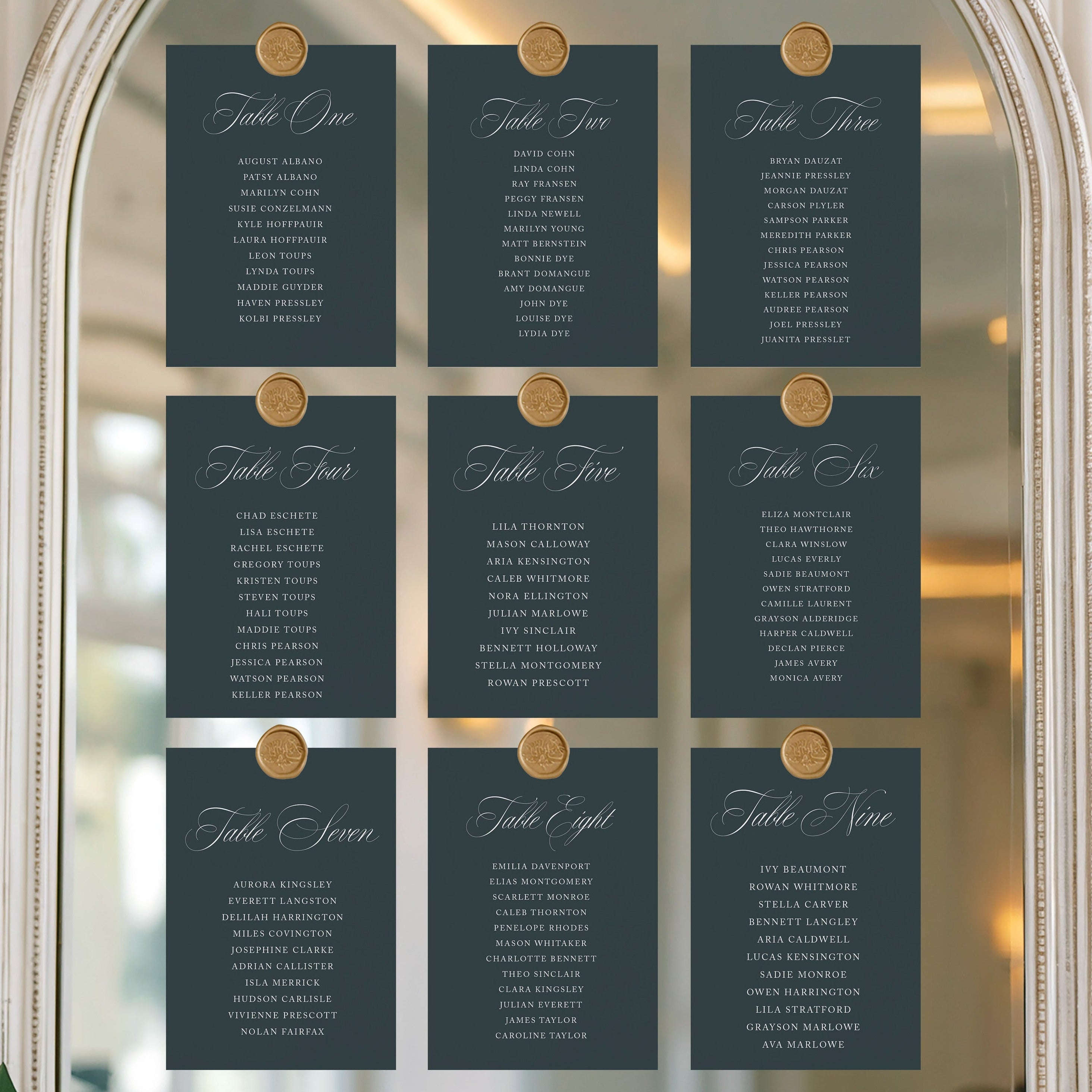 Set of table assignment cards on a decorative mirror with floral decorations.