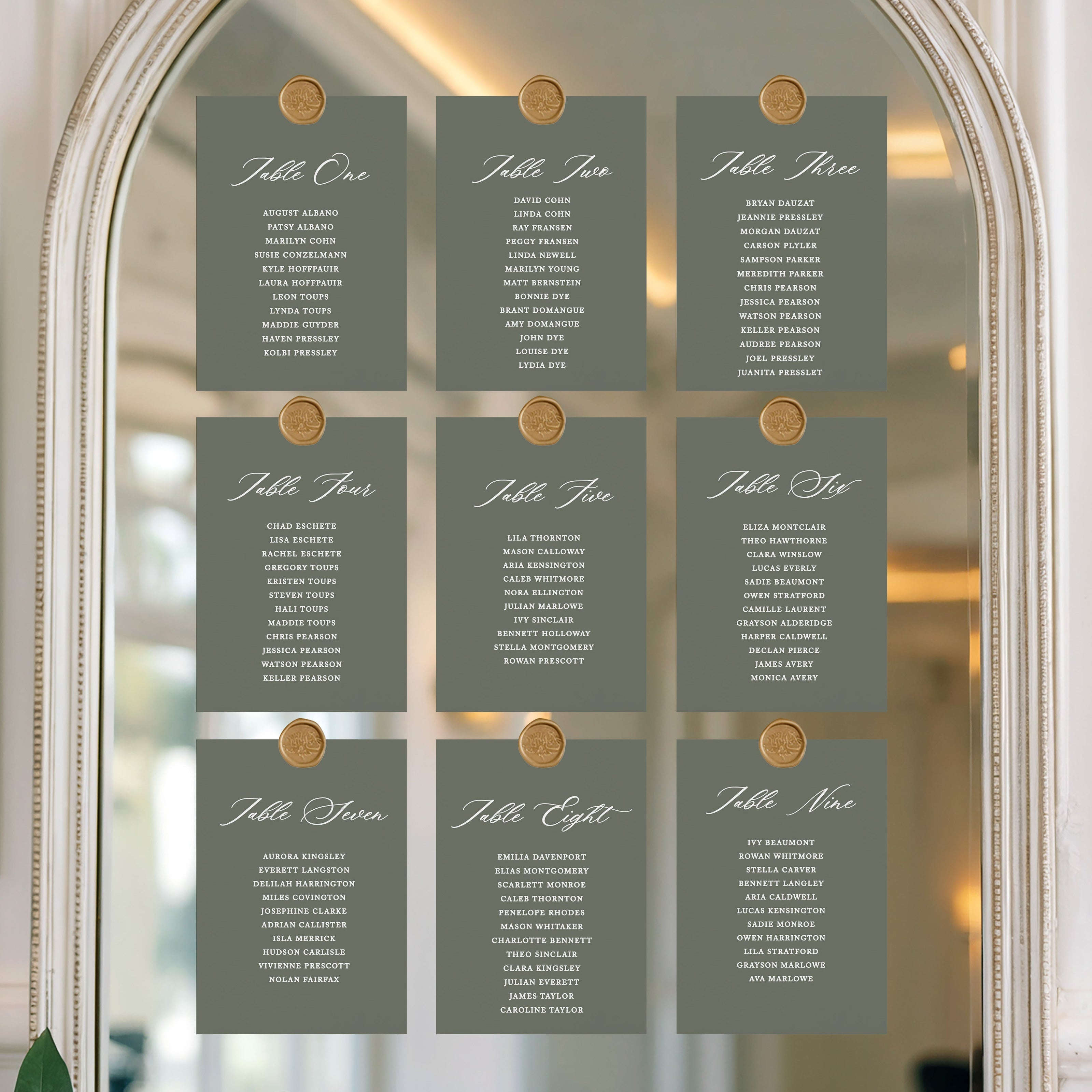 Set of table assignment cards on a decorative mirror with floral decorations.